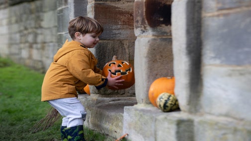 A boy playing with Halloween pumpkin decorations at Seaton Delaval Hall in Northumberland